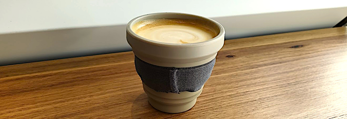 cropped banner-style image of a cup of coffee on a counter