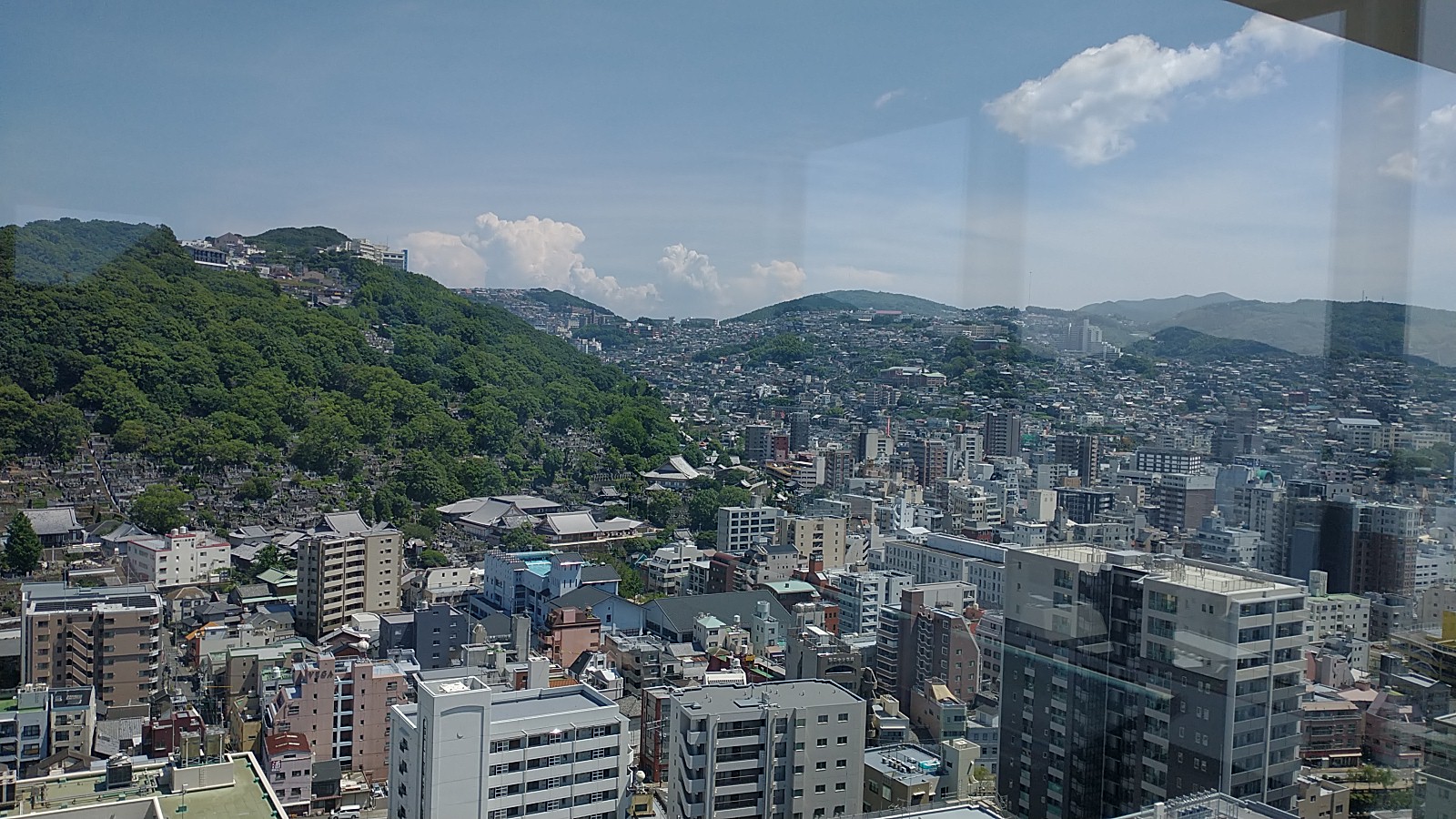 Ignoring the obvious reflection of the glass panel, you can see buildings going into the yonder and around a mountain in the left mid-ground of the picture.